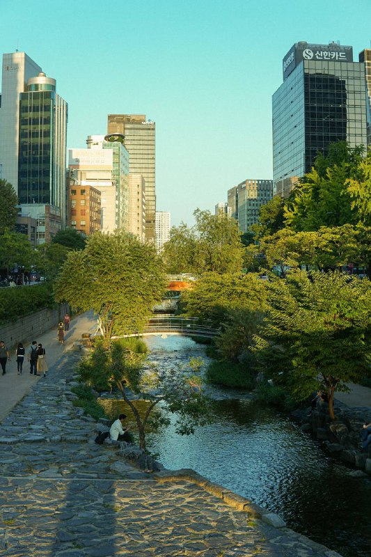 Cheonggyecheon Stream with greenery and an orange bridge